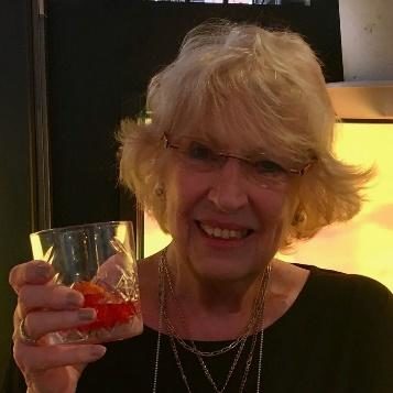 A woman with glasses holding a glass of wine.