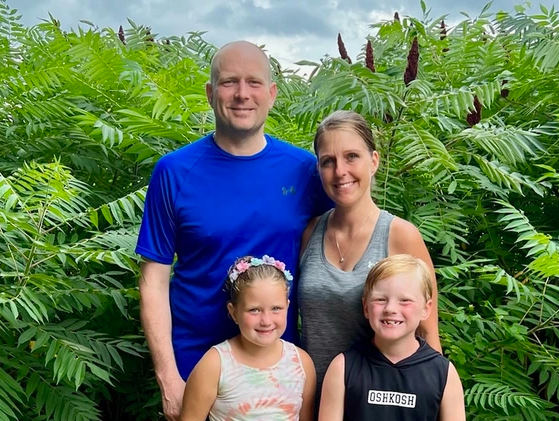 A family posing in front of a field of plants with Glanzmann's Thrombasthenia.