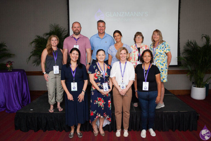 A group of people standing in front of a screen for glanzmann's thrombasthenia awareness.