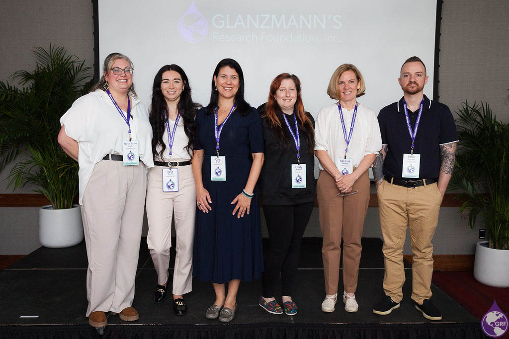 A group of people with glanzmann's thrombasthenia standing in front of a screen.