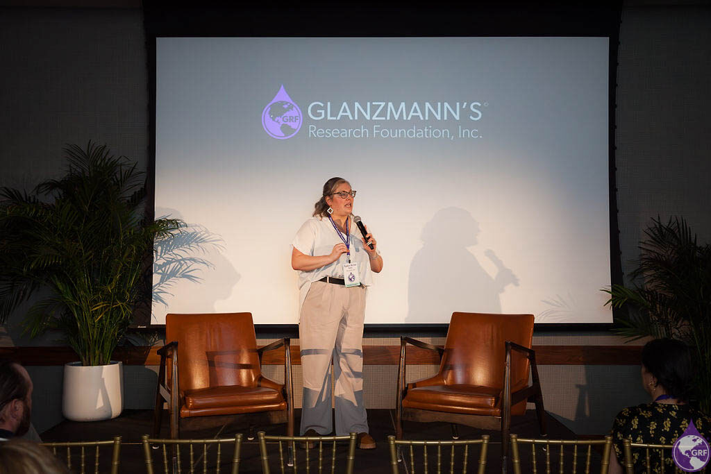 A woman with Glanzmann's thrombasthenia giving a presentation in front of a screen.