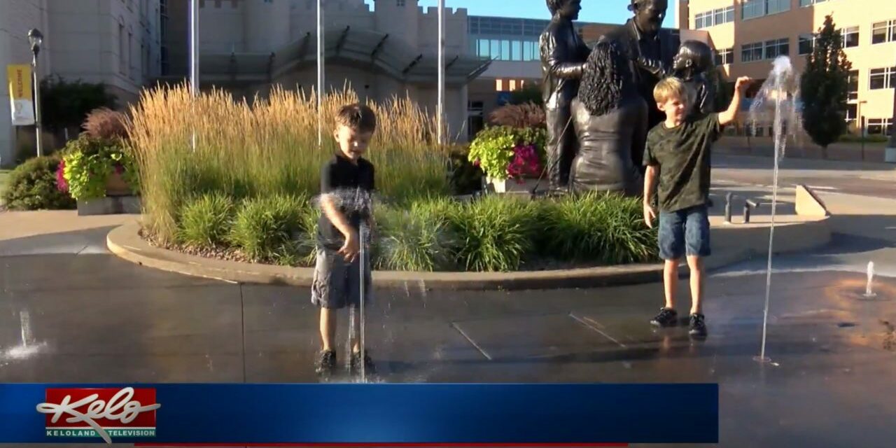 Two boys play in a fountain.